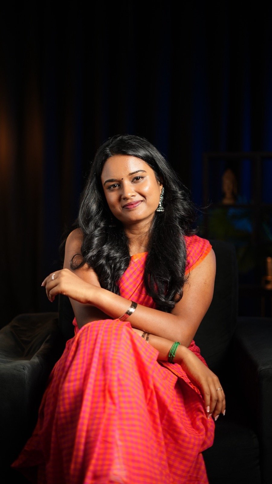Vijayasanthoshini, smiling, seated in a pink sari